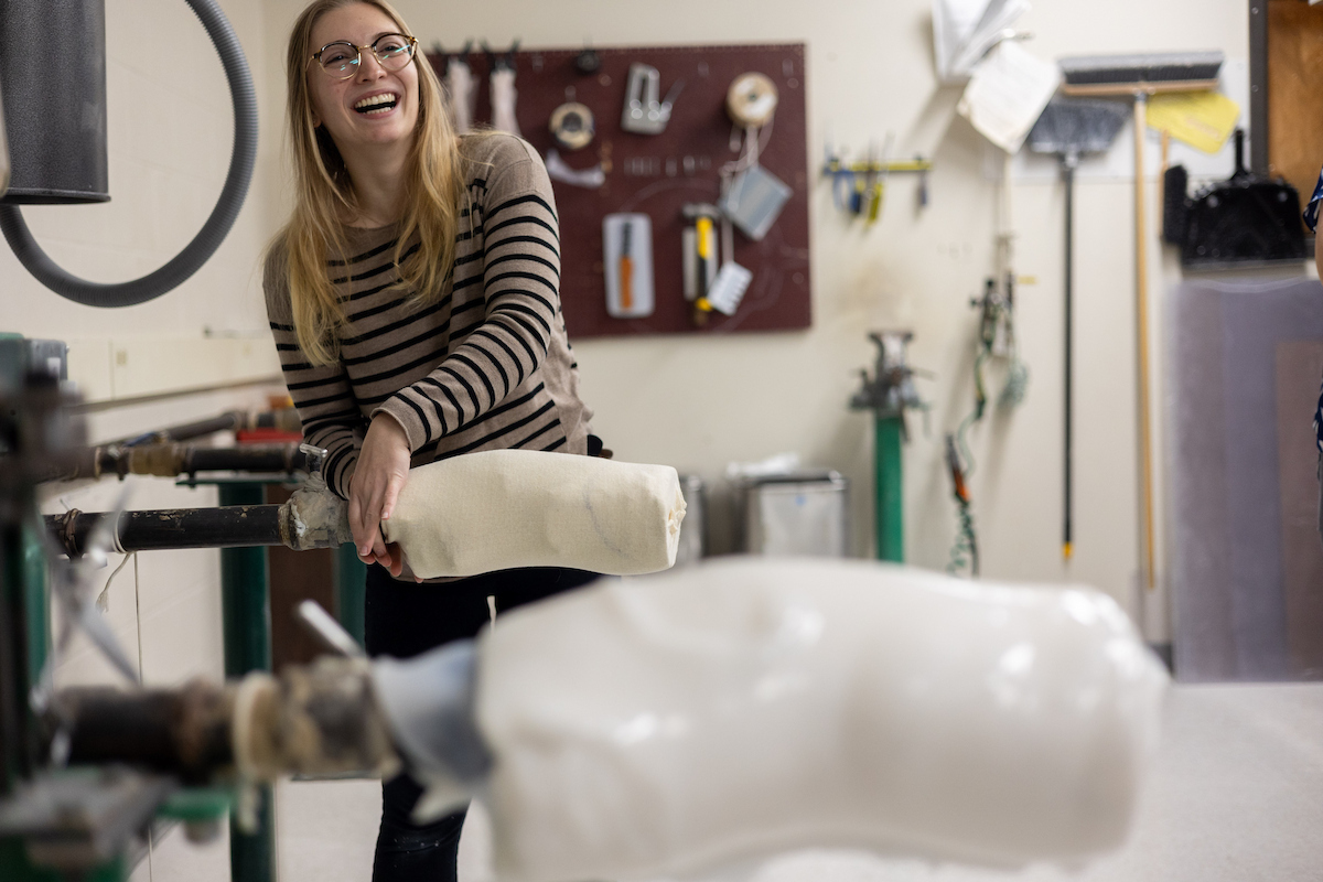 An MSOP student standing at a machine and smiling.